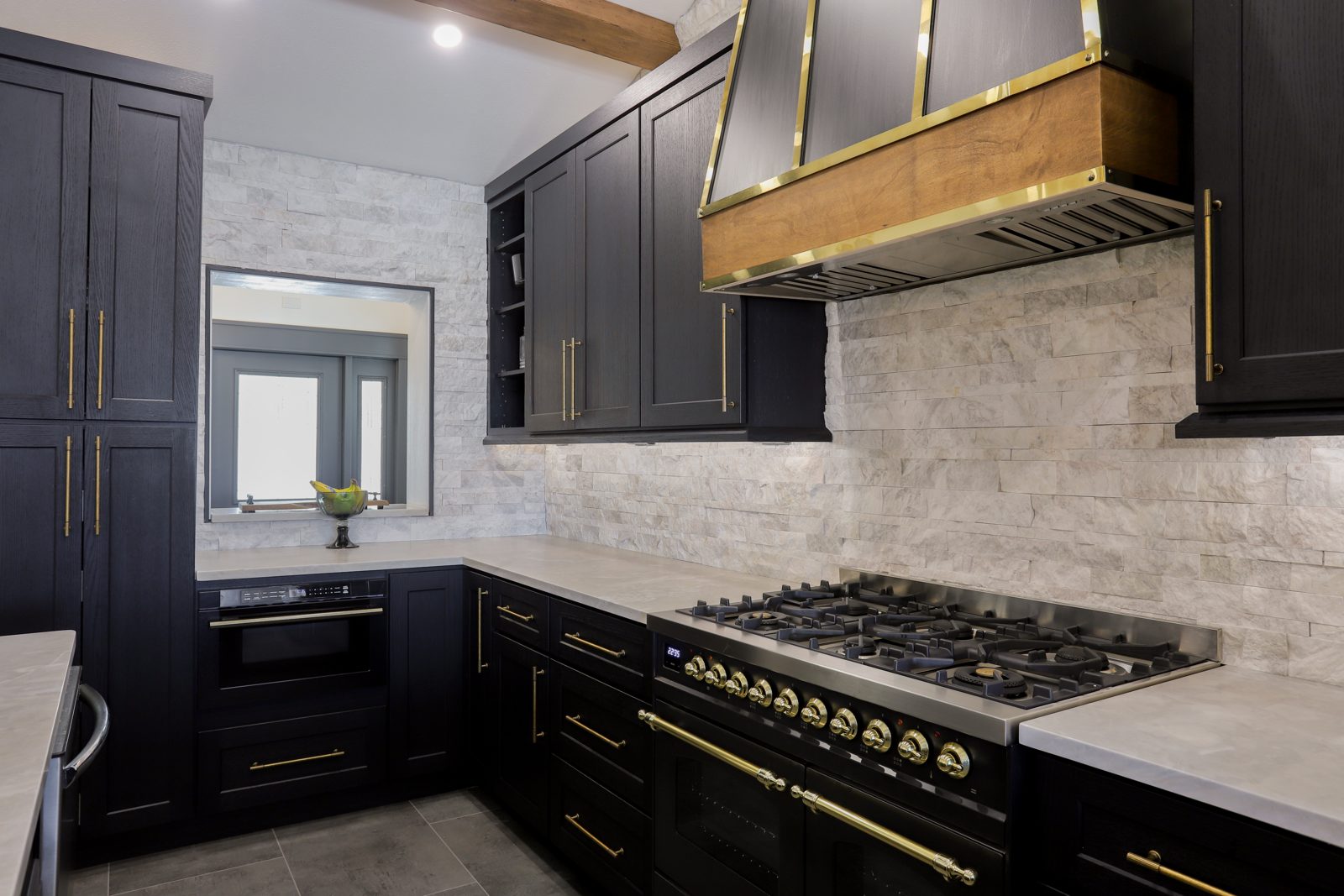 Luxury black kitchen remodel with brass range hood and gas range built by St. Petersburg home builder